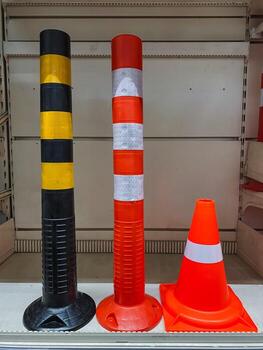 There are three bright and vivid traffic cones neatly lined up on a shelf inside a store, showcasing their vibrant colors and sturdy build designed for safety and visibility photo