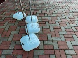 A neat row of white plastic containers is arranged meticulously on a sturdy brick pavement, showcasing a striking design that stands out against the textured surface beneath them photo