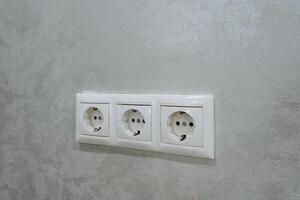 This article discusses the installation of three standard electrical outlets located on a textured wall. It covers aspects like convenience for accessories and appliances in various settings photo