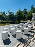 A neat and stylish row of white ottomans is positioned on a wellmaintained wooden deck, adding comfort and elegance to the outdoor living space in a visually appealing manner photo