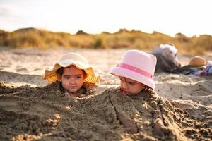 Sisters enjoy a sunny day at the beach while building sandcastles photo
