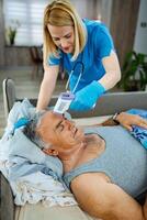 Nurse carefully monitors health of senior man in bed photo