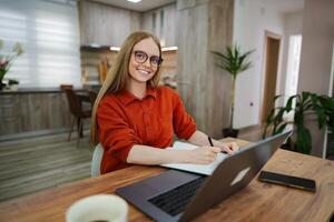 Young woman studies and takes notes in a cozy modern workspace photo