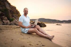 Family enjoys a sunset gathering on the beach with laptop in tow photo