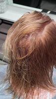 The hairdresser cuts off the ends of long blond red hair and runs a comb. Haircut for long hair in a barbershop close-up. video