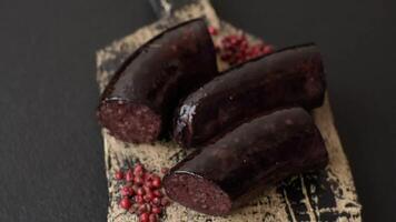 negro sangre salchicha o negro pudín con especias y hierbas A la parrilla en un negro hormigón antecedentes video