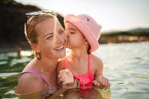 Joyful moments between mother and daughter at the beach during sunset photo