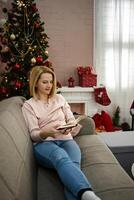 Enjoying a cozy afternoon with a book by the Christmas tree in a beautifully decorated living room photo