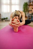 A person practices yoga, reaching for their toes in a sunlit space photo
