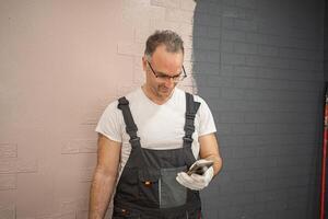 Man in Overalls Painting Brick Wall photo