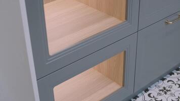 A person's hand is captured opening a modern kitchen cabinet with a classic brass handle, showcasing the intersection of contemporary and traditional design elements video
