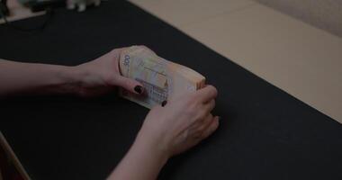 Women's hands skillfully arranging Ukrainian hryvnias in a fan shape while seated at a table in a cozy indoor setting video