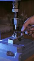 A person using a drill to make a hole in a piece of metal video