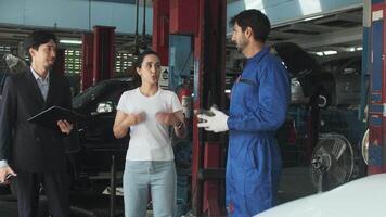 Female customer and Asian male manager discussed technician mechanic about EV car engine fix claims and battery warranty, customer service at automotive garage, and transportation industry. video