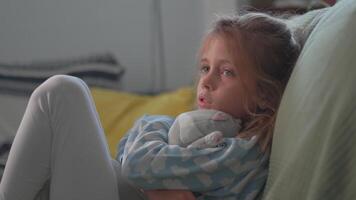 Sick young girl sitting on couch and hugging soft toy for comfort video