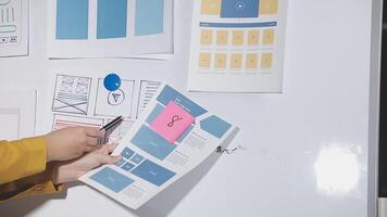 A person is holding a pen and looking at a whiteboard video