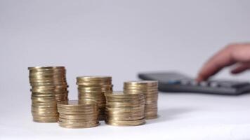 pile di oro monete con un' persona utilizzando un' calcolatrice su il sfondo video