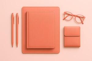 Monochromatic Peach Workspace Notebook Tablet Pen Glasses and Wallet on Peach Background photo