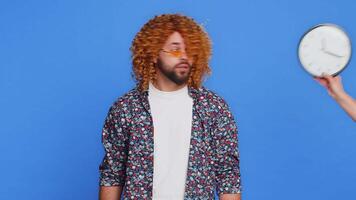 man med lockigt frisyr peruk med ångest kontroll tid på klocka löpning sent till arbete varelse i fördröjning deadline panik. kille ser på timme, minuter, oroande till vara punktlig isolerat på blå bakgrund video