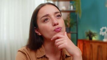 Young woman at home table stares ahead resting chin on hand and thinks hard about solution and plan. Caucasian girl searches mind for idea and weighs options hoping insight will arrive soon video