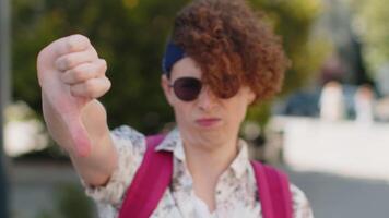 disgusto. trastornado joven hombre en Gafas de sol demostración pulgar abajo firmar gesto, expresando descontento, desaprobación, insatisfecho malo trabajar, error. disgustado chico en urbano ciudad Brillo Solar calle al aire libre. video