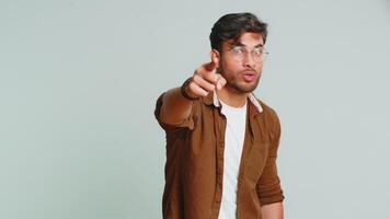 jag välja du. indisk leende man pekande finger till kamera och ser med lekfull Lycklig uttryck, framställning vinnare val, som visar riktning. arab ung kille isolerat på grå studio bakgrund video