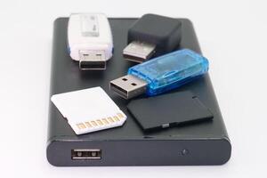 Collection of various data storage devices on a black portable hard drive displayed on a white background photo
