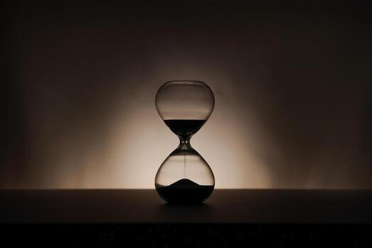 A simple hourglass on a wooden table with a beige backdrop, symbolizing time flow and minimalistic living. Running out of time, uncluttered presentation for stylish concepts photo
