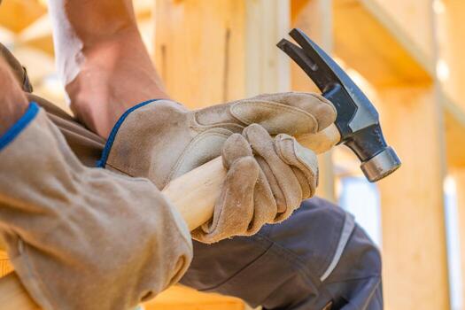 Skilled Worker Using a Hammer to Construct Wooden Framework at a Building Site photo