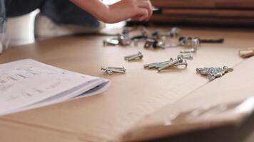 mani ordinamento e assemblaggio mobilia pezzi utilizzando noccioline e bulloni su un' di legno tavolo con istruzione Manuale video