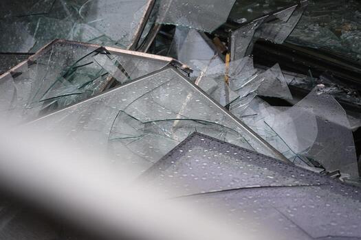 Broken shattered windows and glass panes lie in a container for disposal in the rain photo