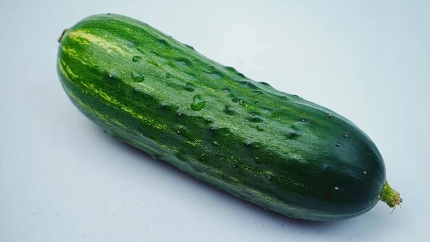 white background is a fresh green cucumber with small thorns on the skin. Its smooth texture and bright color emphasize naturalness and draw attention to healthy eating. photo