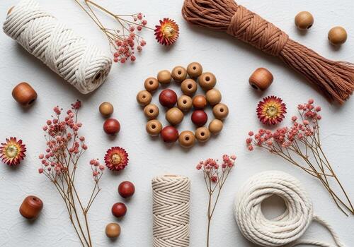 Craft materials arrangement with beads, twine, and dried flowers on white background photo