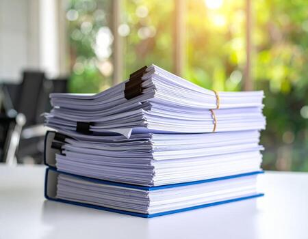 Stack of papers and reports cluttering a desk in an office setting photo