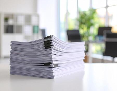 Office desk cluttered with stacks of reports and documents against a background of paperwork photo
