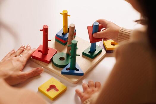 Child and parent playing with a colorful wooden educational toy, improving motor skills and learning shapes through hands on interaction, logic games photo