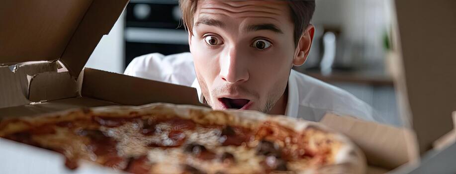 A man is looking at a pizza in a box photo