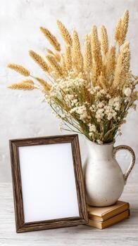 Dry wheat in a vase with a blank frame on a wooden table photo