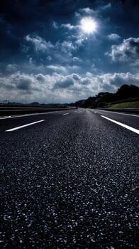 An empty road with a bright sun shining in the sky photo