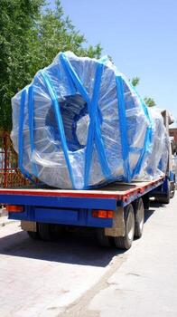 A large blue truck with a large object wrapped in plastic photo