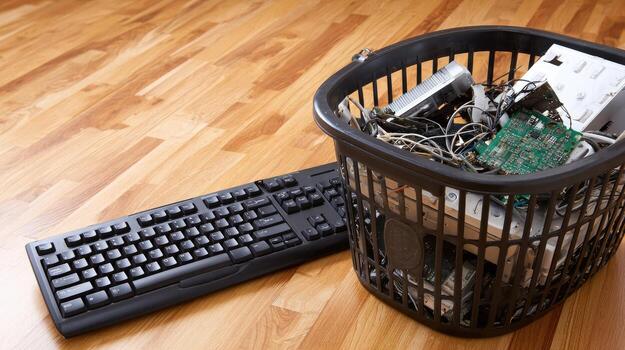 A computer keyboard and a trash can with electronics photo