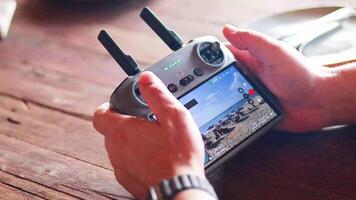 händer rörelse en Drönare kontrollant på en trä- tabell i phuket, med ljus belysning och en fokus på de skärm video