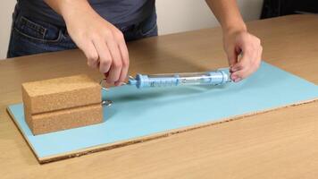 A person uses a spring scale to measure frictional force on a wooden block across a surface video