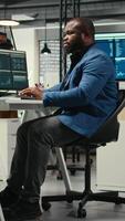 vertikal afrikansk amerikan manlig analyserar finansiell data prognos på en dator, utvecklande innovativ företag lösningar för inriktning med företag mål. professionell miljö. kamera a. video