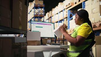 svart kvinna placering lim sändning taggar på kartong lådor, handtag märkning och förpackning uppgifter för beställa bearbetning. arbetstagare applicering tryckt awb etiketter i lagring depå. kamera a. video