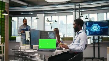 tekniker Nästa till kontor medarbetare utvecklande programvara tillämpningar använder sig av grön skärm bärbar dator, integrering ai automatisering. den expert- felsökning tillämpningar med attrapp anteckningsbok, kamera en video