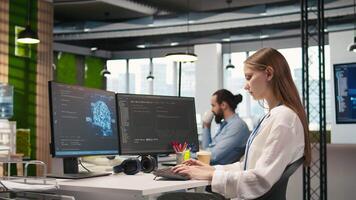 jung weiblich Programmierer im Büro Überprüfung ai System Metriken, Hören Musik, Überwachung Performance Dashboards. Junior dev tragen Kopfhörer Tuning neural Netzwerke mit Werkzeuge auf PC, Kamera ein video