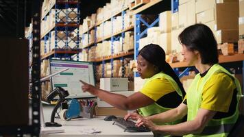 team av två arbetare övervakning frakt rutt på spårning programvara, pekande på de pc övervaka och uppdatering de paket sändning detaljer. skriver logistik data på dator. kamera a. video