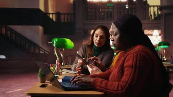 Focused students taking notes from academic library resources and reviewing archived materials in a study area, showing the dedication of mature education and knowledge building. Camera A. video