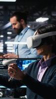 vertikal data Centrum ingenjör använder sig av virtuell verklighet, hantera ai system för drifttid och effektivitet. den anställd använder sig av vr headsetet och artificiell intelligens teknologi i server nav, kamera en video